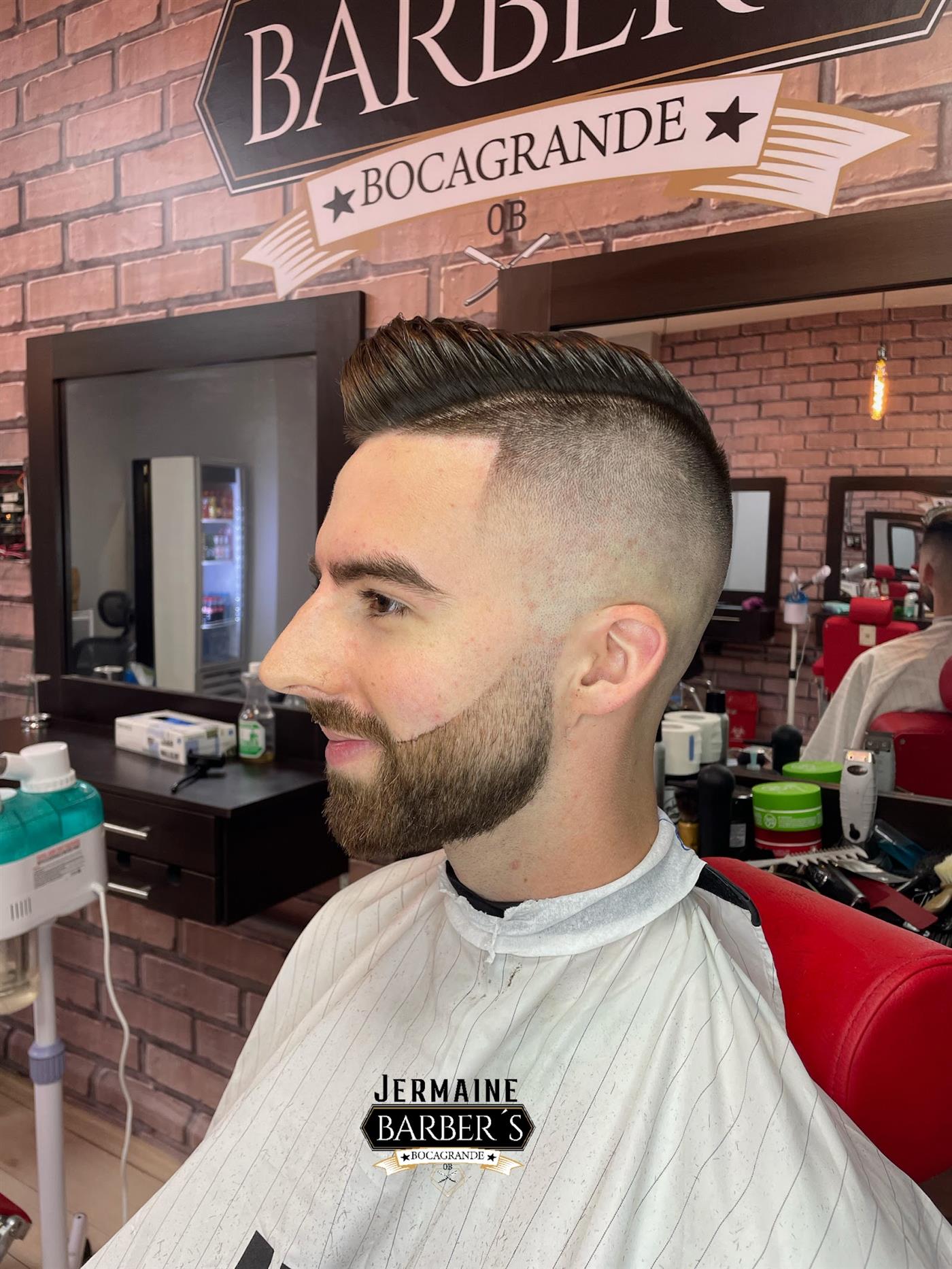 Cliente con barba perfilada frente al espejo con el letrero Bocagrande